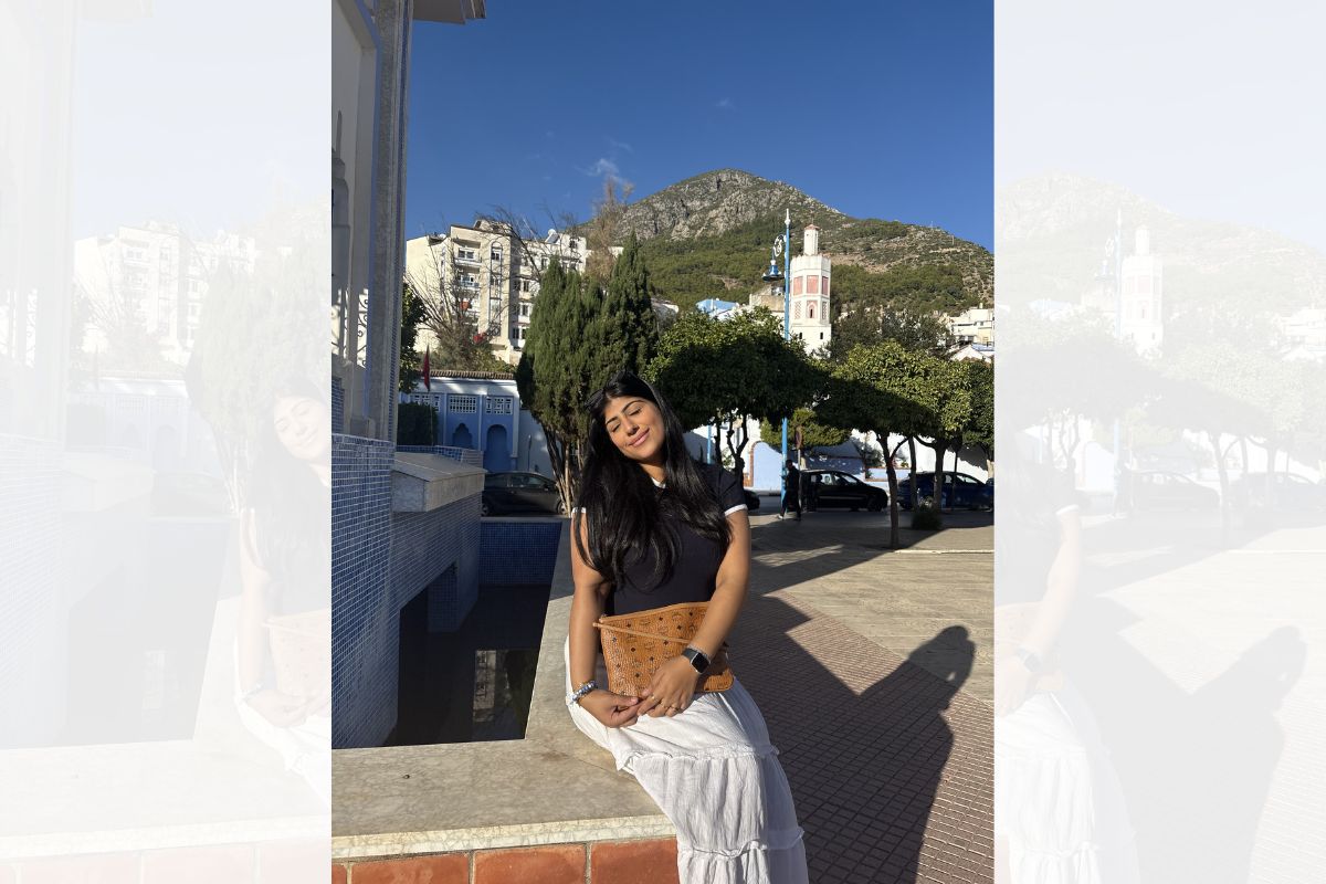 A woman sitting down in the sunshine, smiling, with her eyes closed.