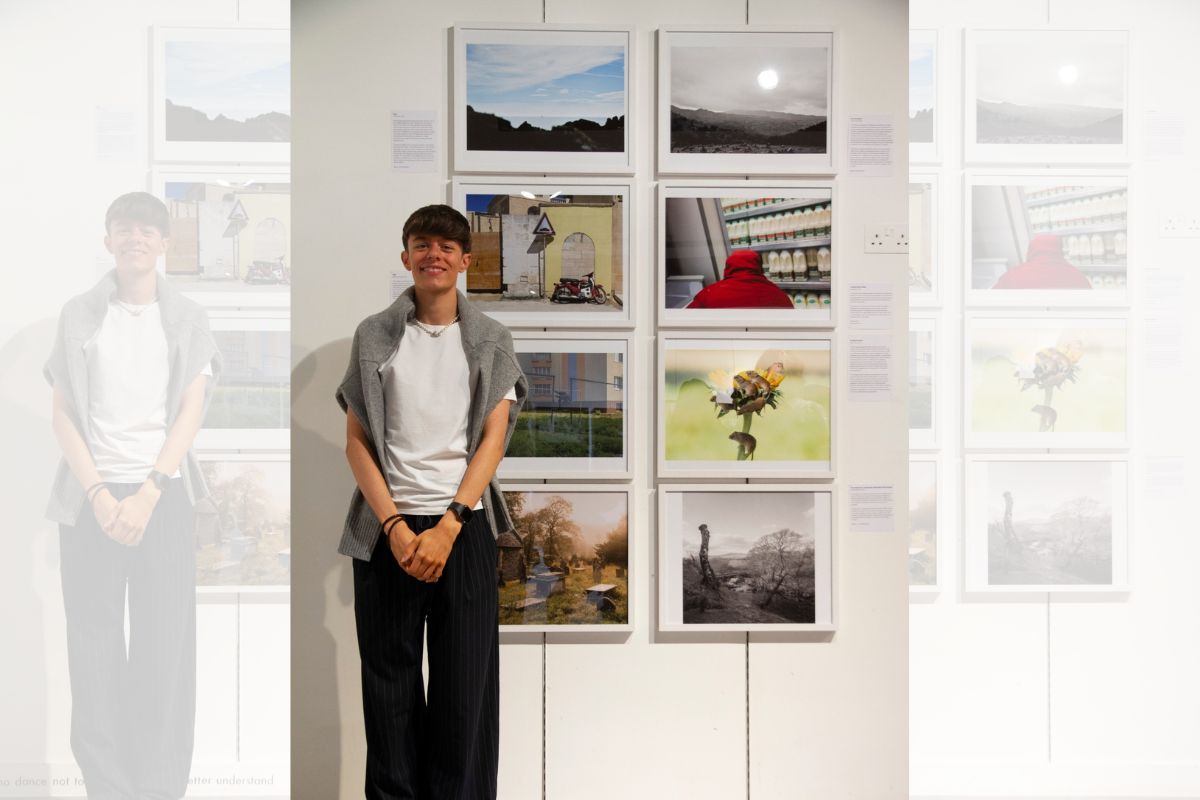 Photography student, Adi Gorman, in front of several photos.