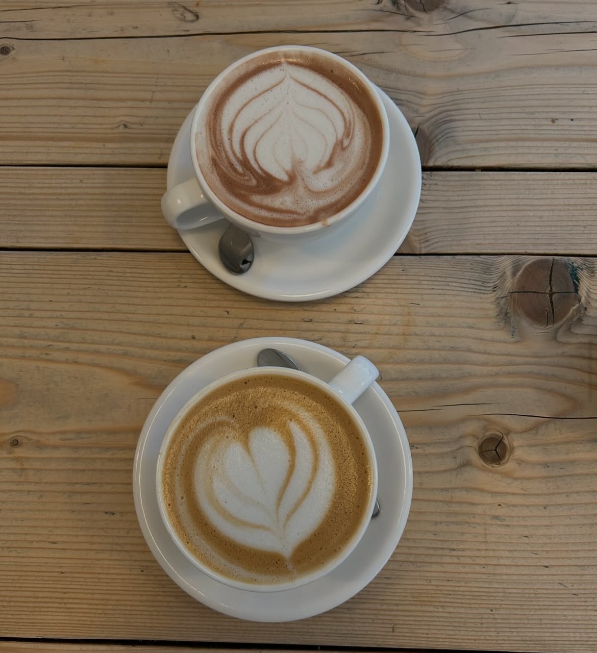 Two espresso-based drinks with latte art on a wooden table