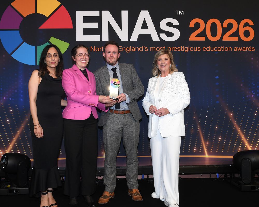 Two people from the University of Chester collecting an award on stage at the ENAs. Also present is awards host Lucy Meacock. In the background is the logo for ENAs 2026.