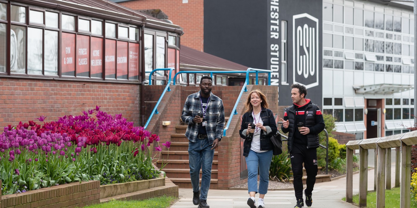 Three students walking through the University of Chester grounds