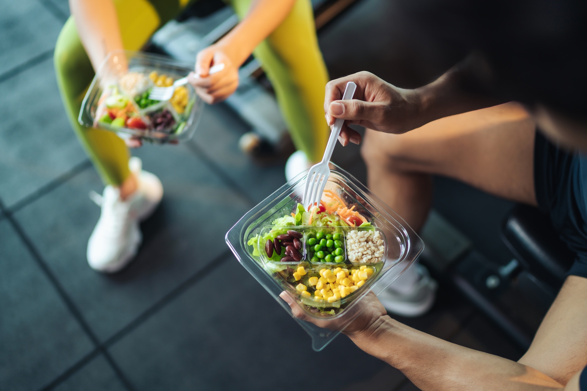 man and woman healthy eating salad after exercise at fitness gym