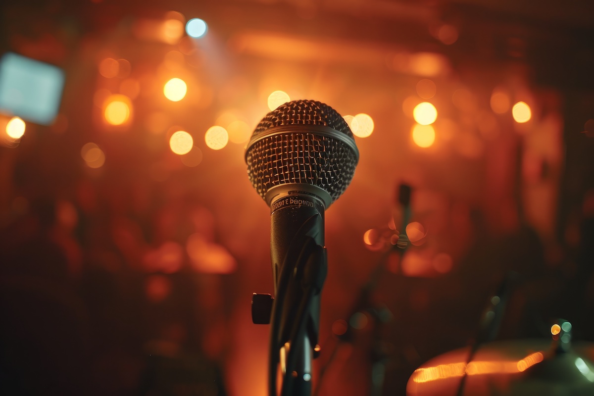 A close-up view of a microphone placed in front of a stage with colorful lights