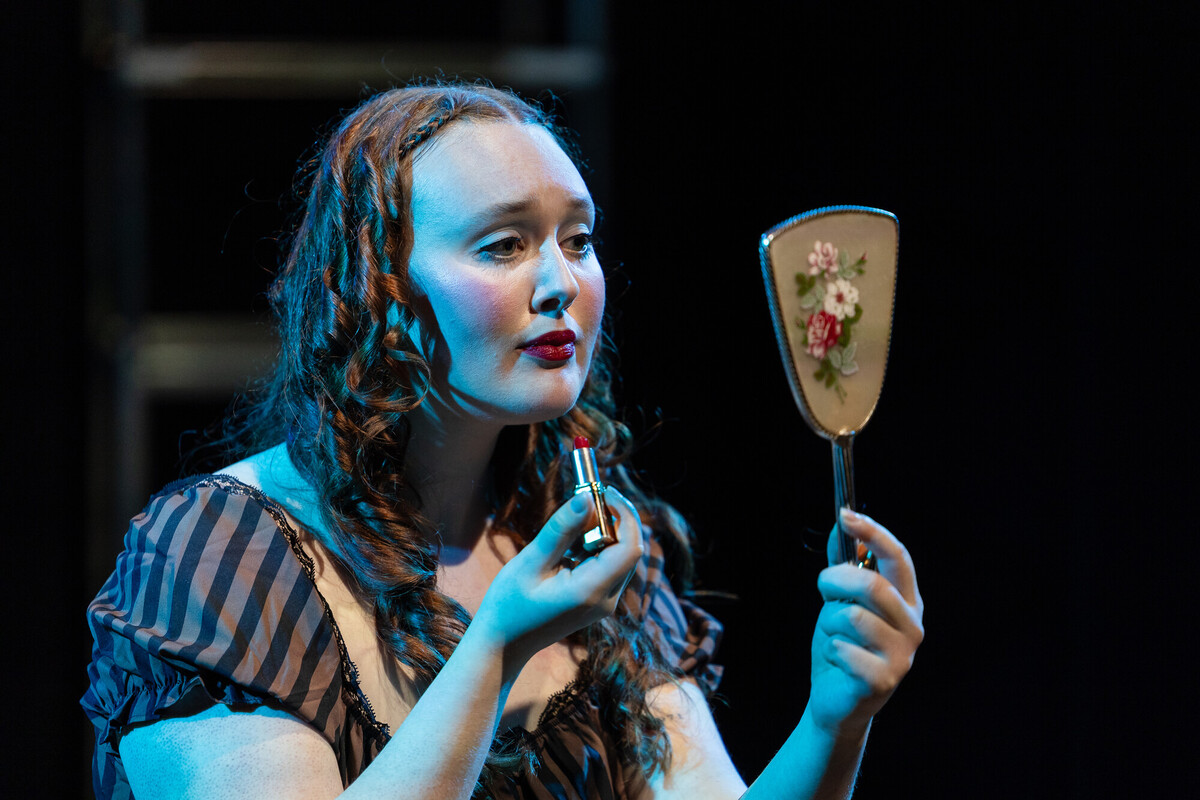 female student putting on makeup on stage