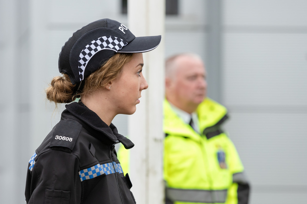 A female and male are standing outside in police line.