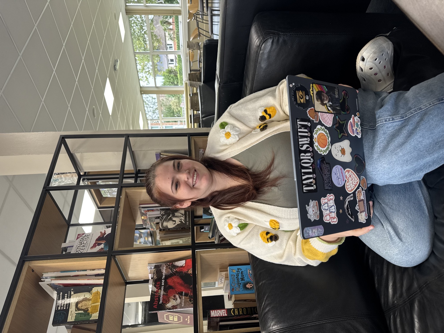 Combined Honours student Louisa sitting on a couch and holding a laptop