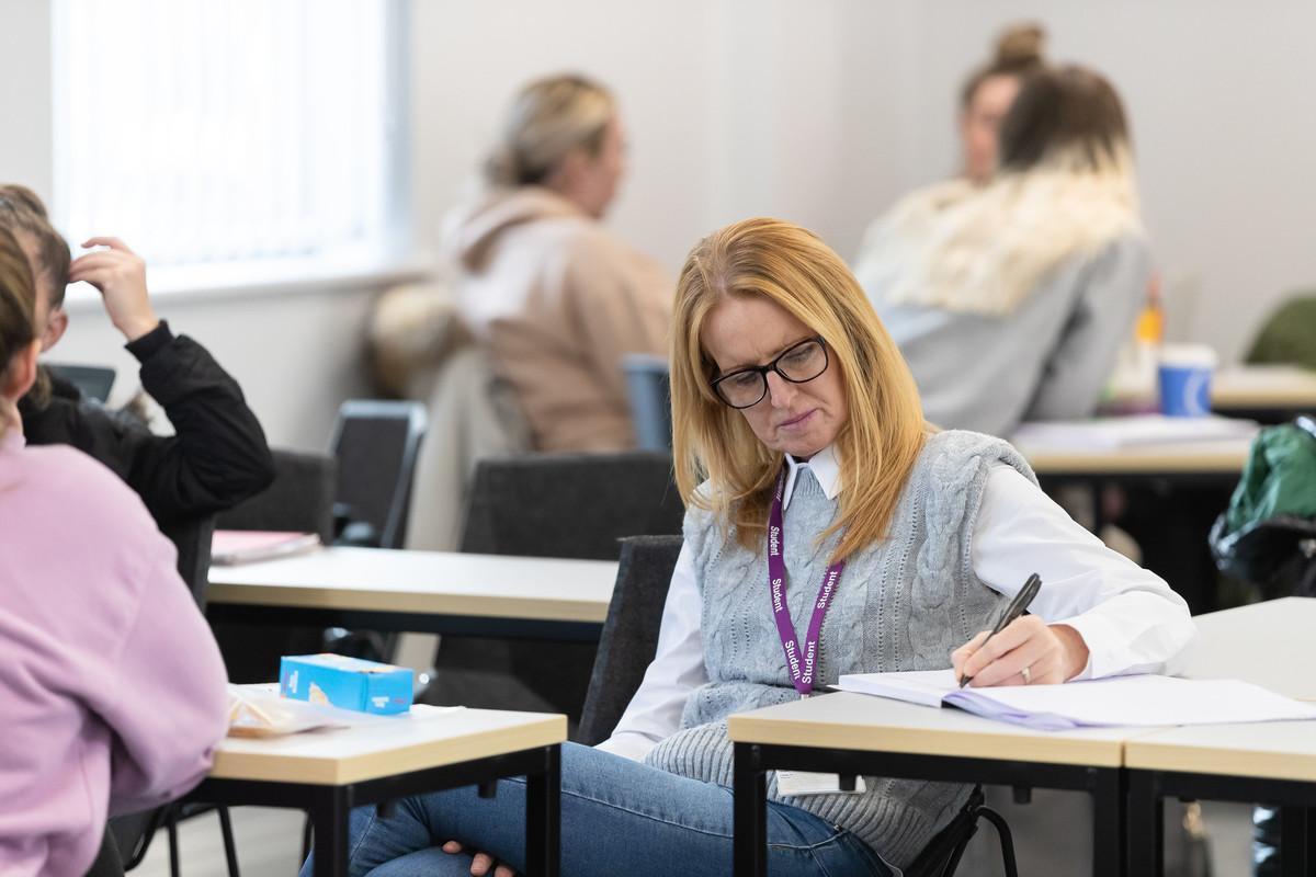 University of Chester student taking notes during a Psychology and Sociology BSc (Hons) class, focusing on human behaviour and social dynamics.