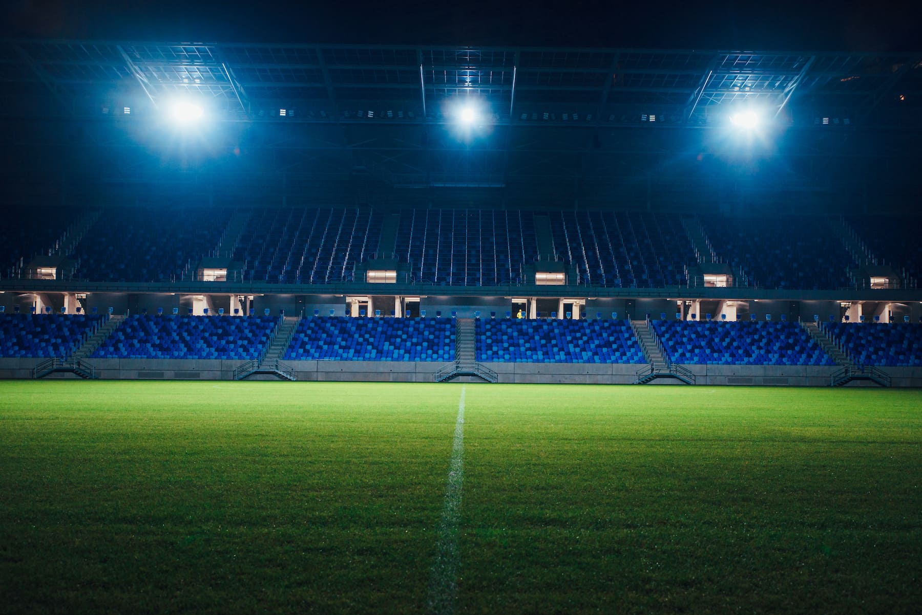 An empty football stadium at night with floodlights on