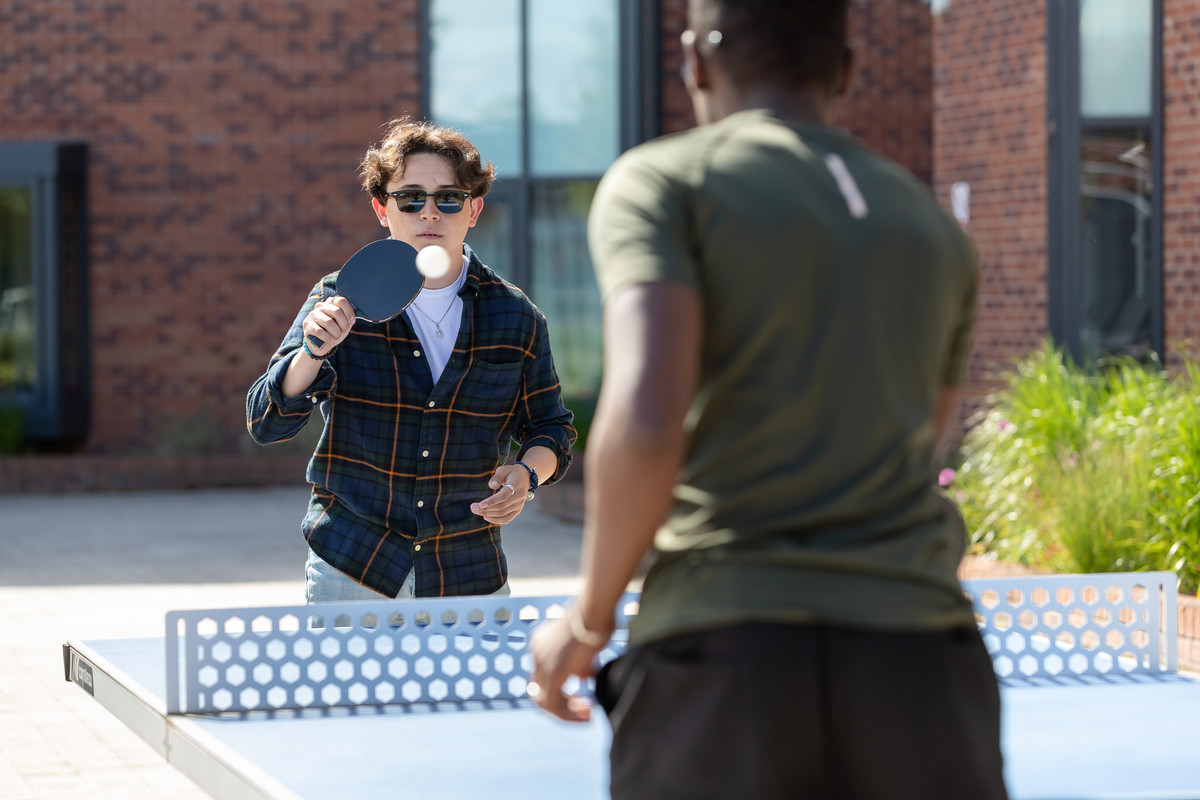 Two students playing table tennis outside