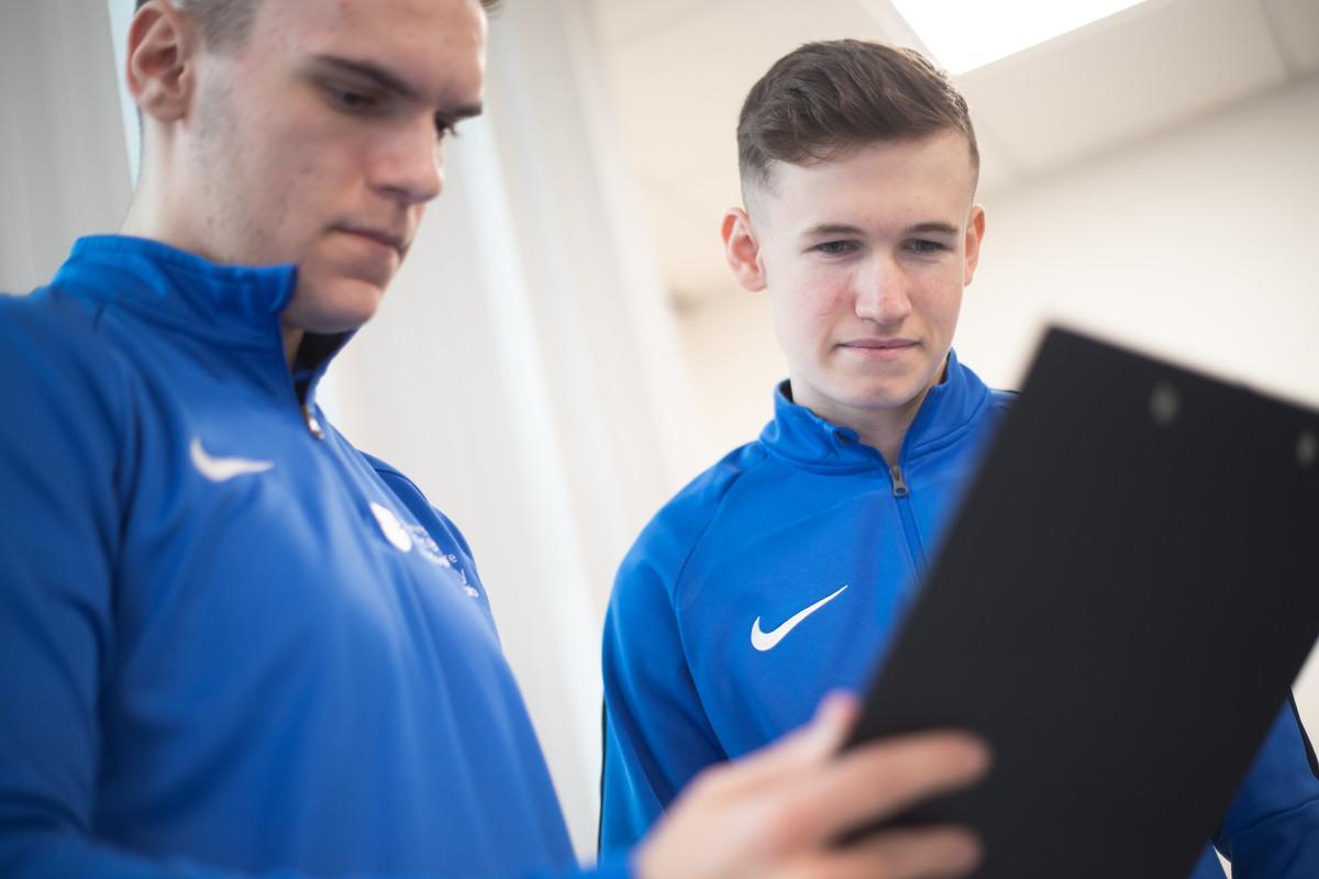 Sports Medicine MSc students reviewing athlete assessment data on a digital tablet in a clinical learning environment, demonstrating evidence-based practice, sports injury management, performance monitoring and applied sports medicine research.