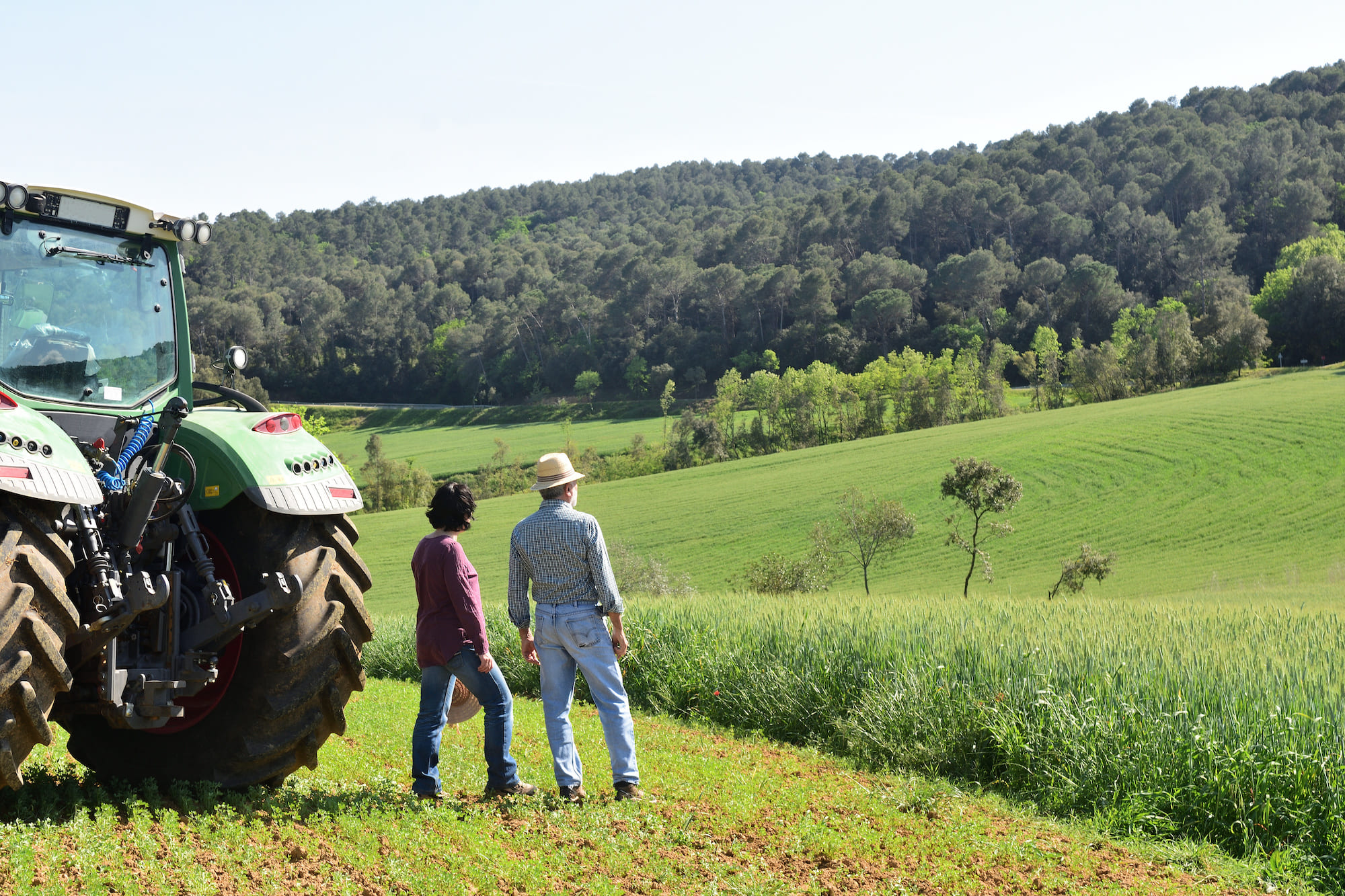 Two farmers in front of tractor in a field
