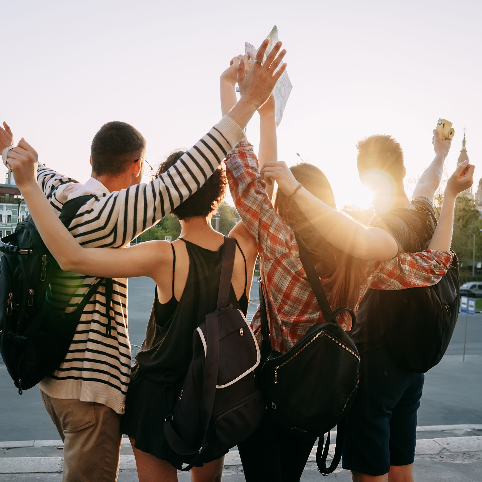 People with backpacks rising hands, joy and positivity.