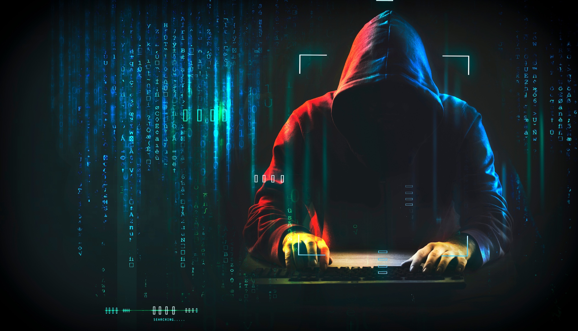 Hooded figure typing on a computer keyboard with computer code symbols and graphics around the figure