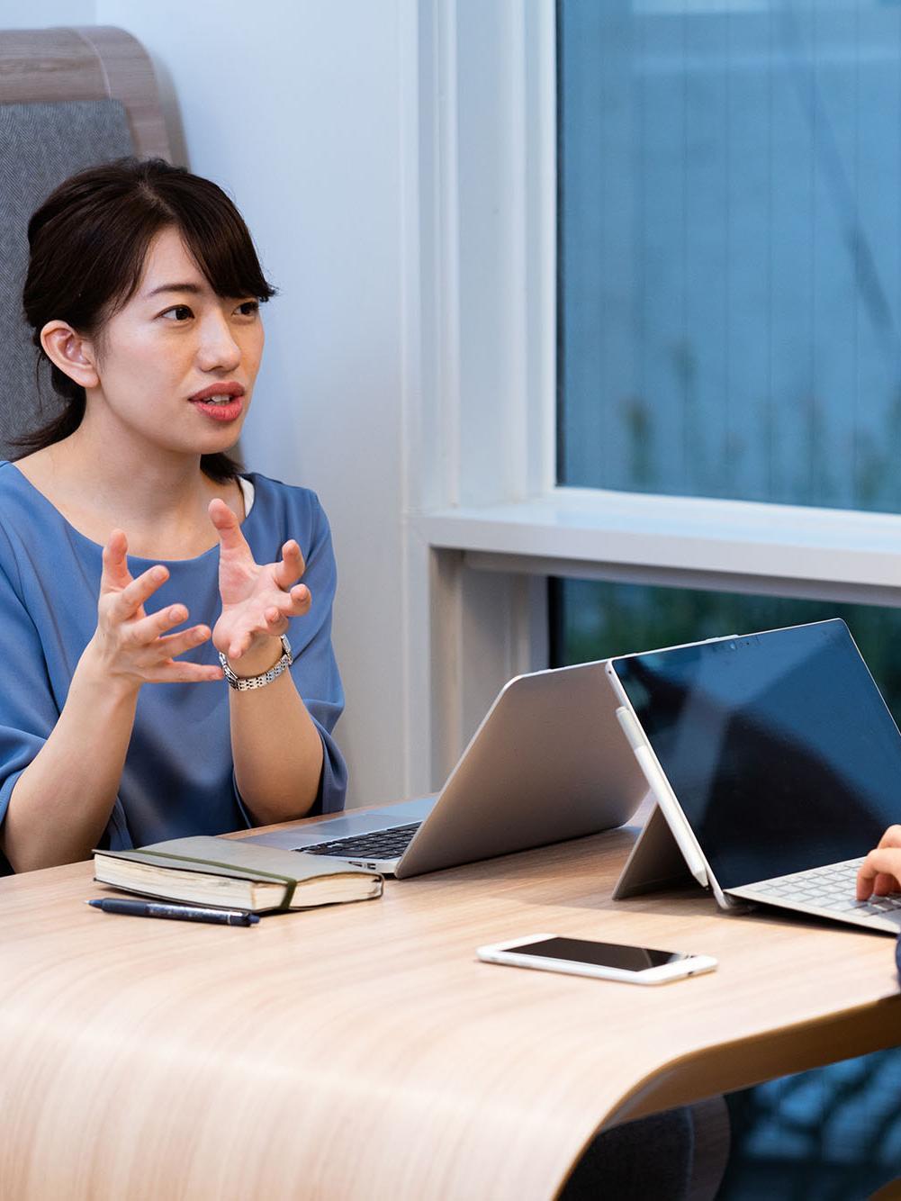 Two business people having a discussion while one is typing up on their tablet.