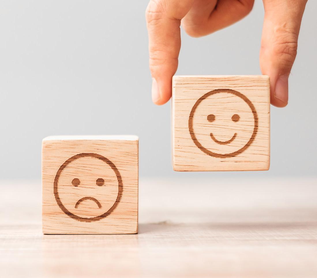 Close-up of wooden emotion blocks showing sad and happy faces, symbolising psychological wellbeing, behaviour change and mental health studies for Psychology (Conversion) MSc students at the University of Chester.