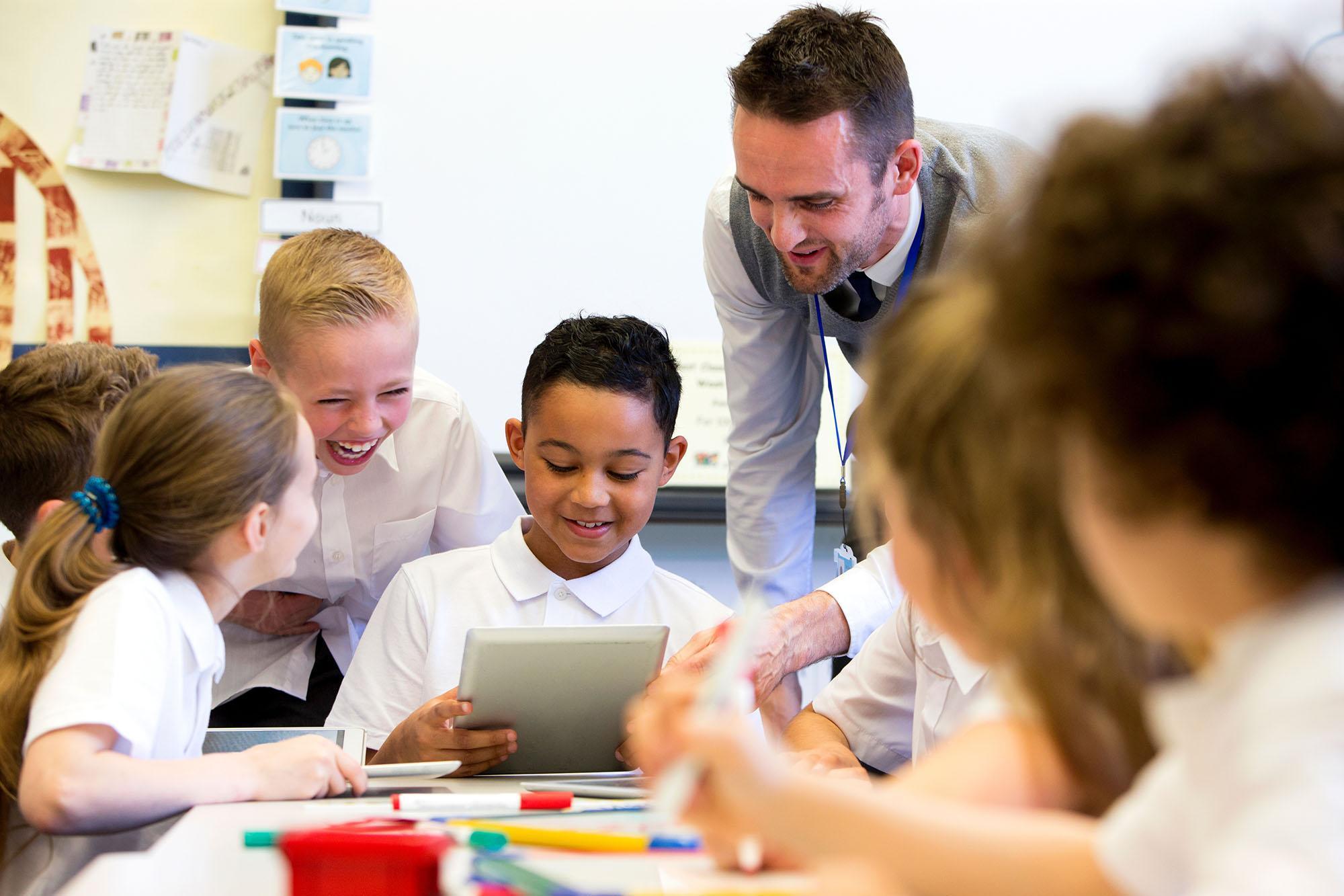 Professional supporting primary-aged pupils in a classroom setting, demonstrating inclusive practice and child-centred approaches relevant to the Mental Health, Trauma and Attachment PGCert at the University of Chester.