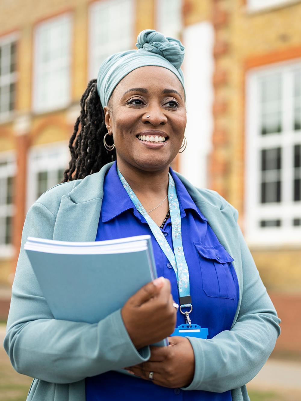Doctor of Education (EdD) student standing outside a university building, holding study materials. Advance educational leadership, professional practice and research expertise with the University of Chester's Doctor of Education EdD programme.
