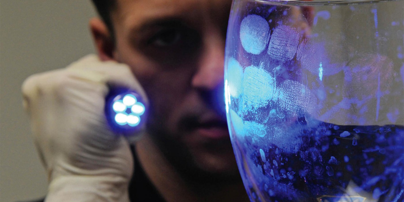 A person uses forensic equipment to examine an object