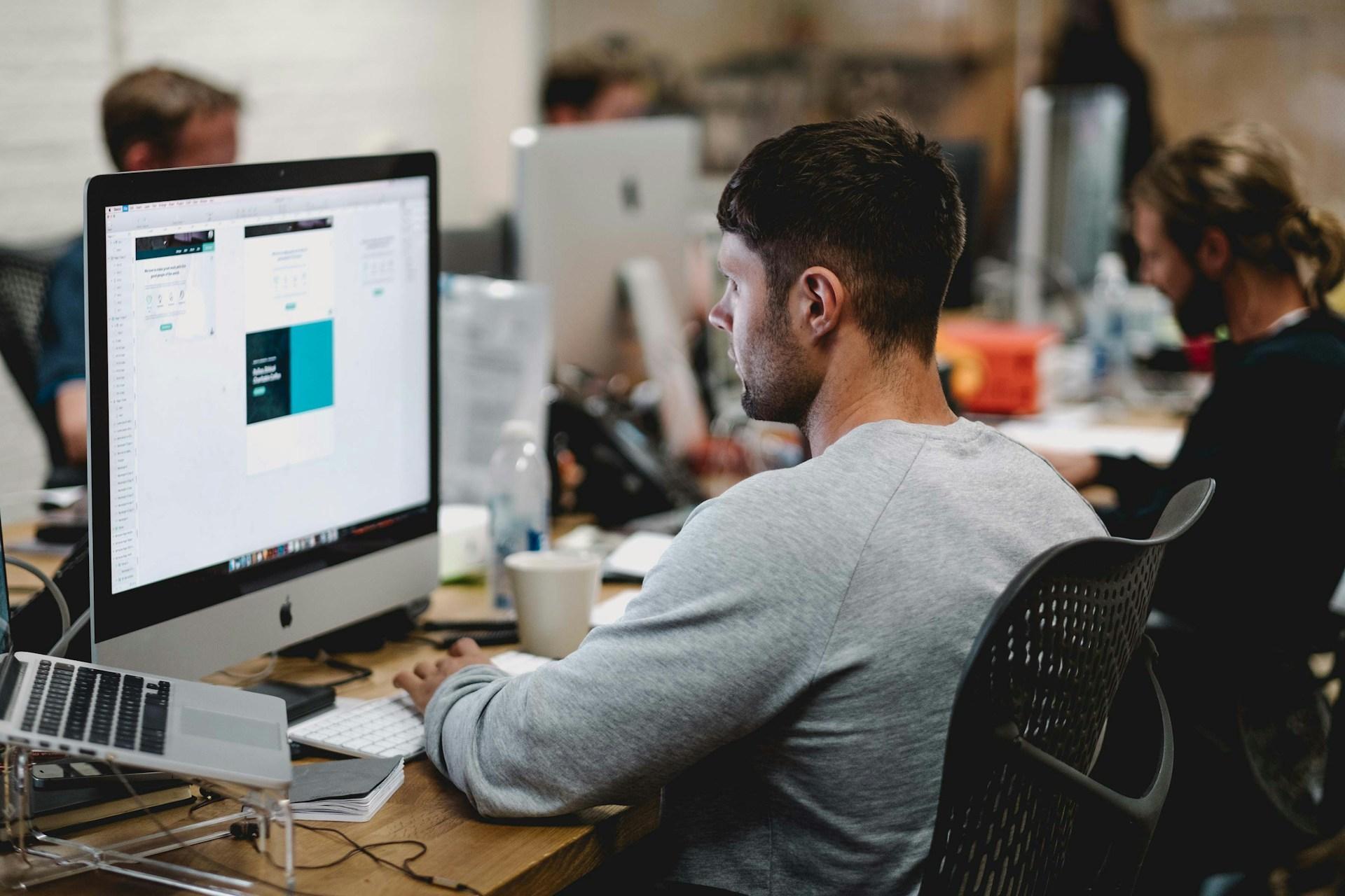 Geography graduate working in an open-plan office using digital tools to analyse spatial data, reflecting career pathways in GIS, urban planning, and environmental consultancy.