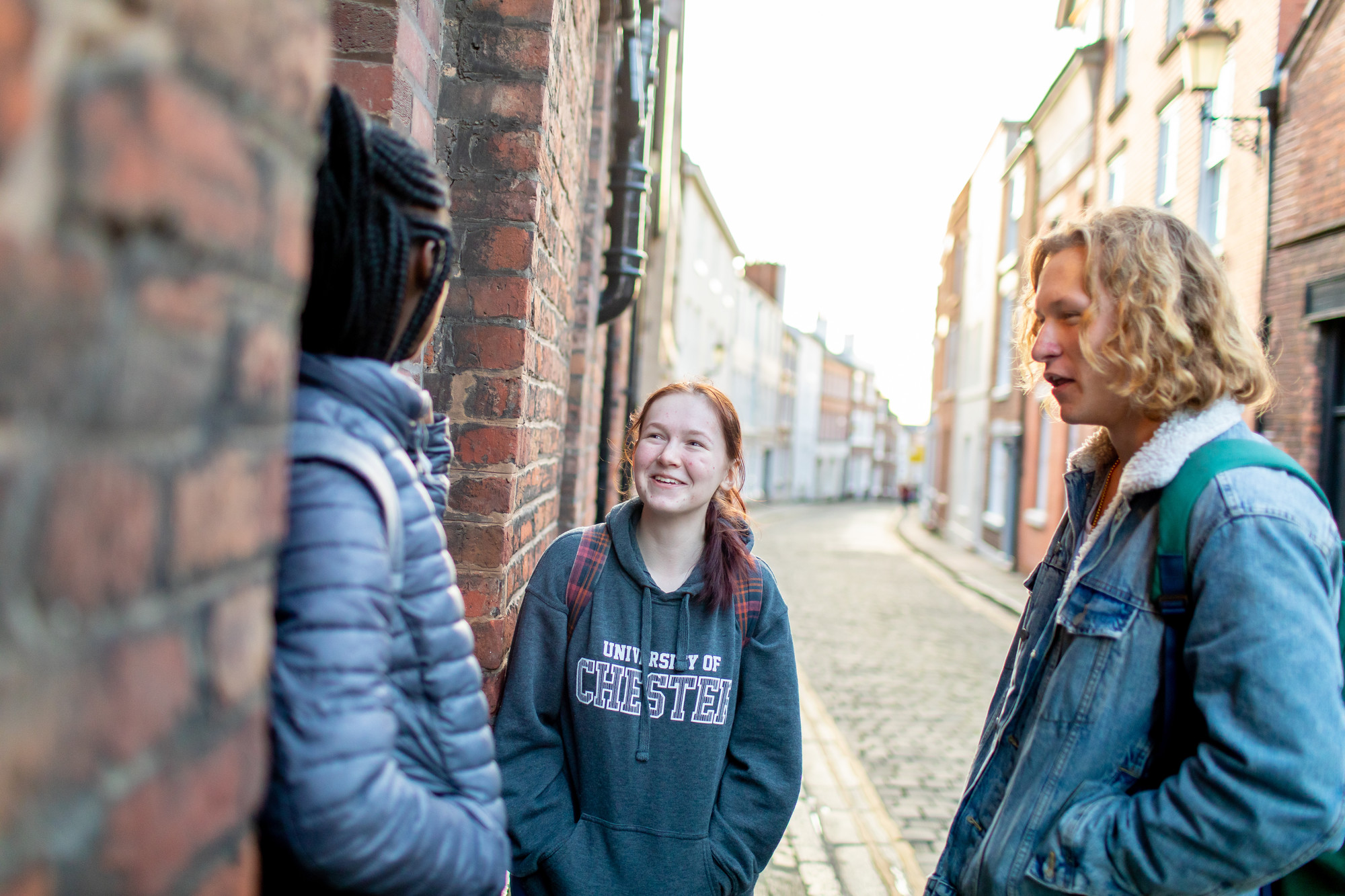 three students standing on a quiet cobbled street in chester