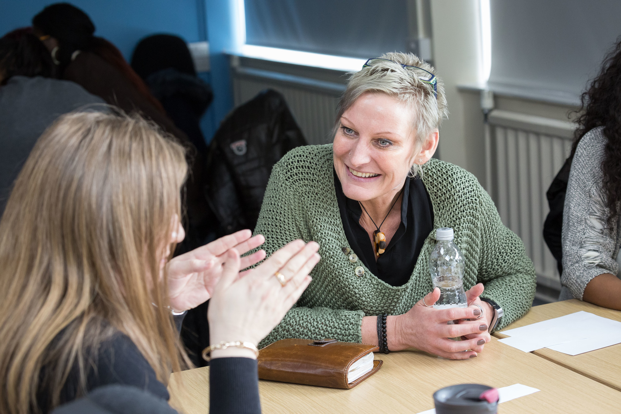 Two mature students sitting at a table, smiling and talking