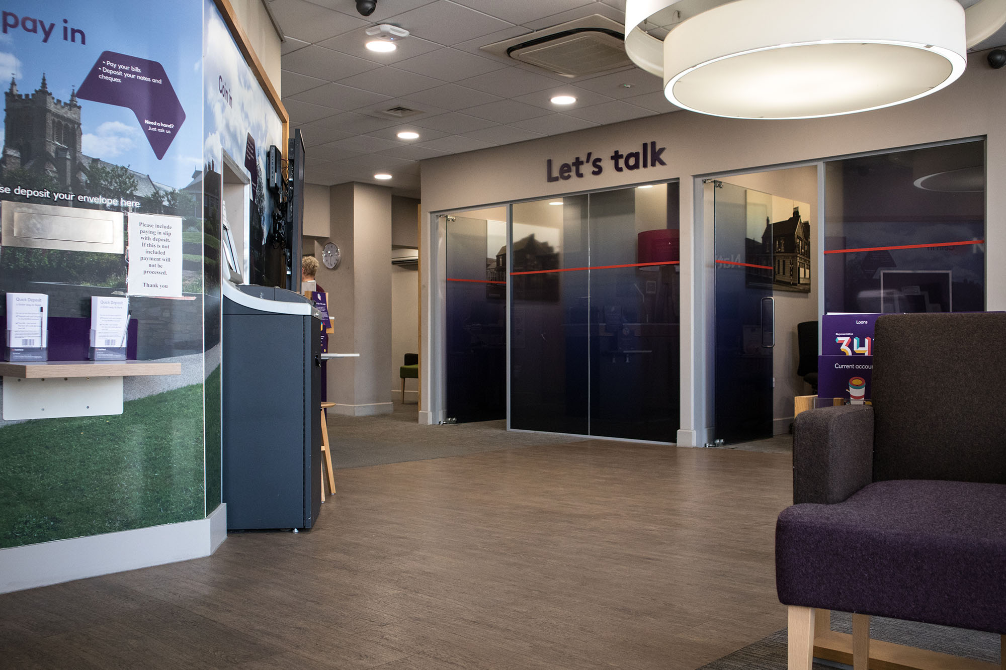 Modern bank branch interior with self‑service deposit machine, customer seating area, and private consultation rooms, showcasing UK retail banking services and in‑branch customer support.