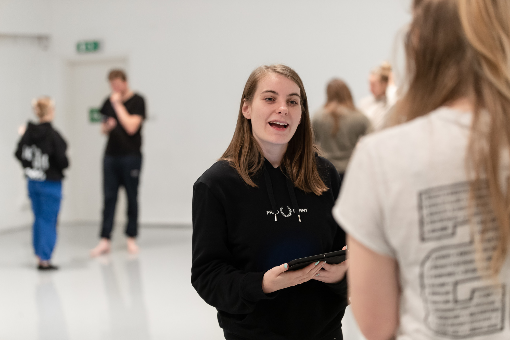 A female student holding ipad, talking to a person in front of them
