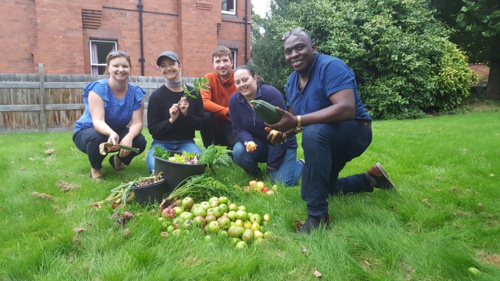 Staff and students kneeing in front of lots of produce, apples, carrots, courgettes, grown in the allotment